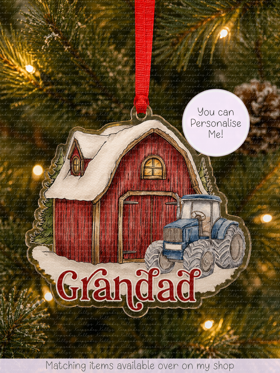 A personalized Christmas ornament shaped like a red barn with a blue tractor and snow, hanging on a Christmas tree. The ornament has the name 'Gréndad' written in red script and a white circular sticker that says 'You can Personalise Me!'.