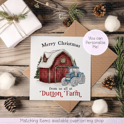 A personalized Christmas greeting card featuring an illustration of a red barn and blue tractor on a rustic wooden tabletop with a kraft envelope, wrapped gift, pine branches, and decorative props.