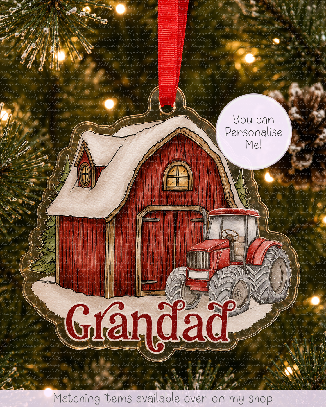 A personalized Christmas ornament shaped like a red barn with a tractor and snow, hanging on a Christmas tree. The ornament has the name 'Grandad' written on it and a red ribbon at the top.